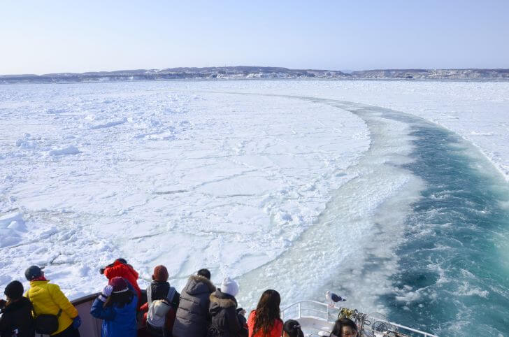 流氷の間をゆく砕氷船。青い航跡を描きます。