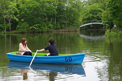 湖畔の乗り場から手こぎボートに乗るカップル