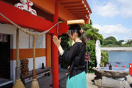 釜蓋を頭に載せ礼拝する女性