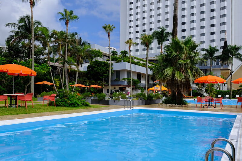 ヤシの木と豊かな緑や花々に囲まれた屋外プール