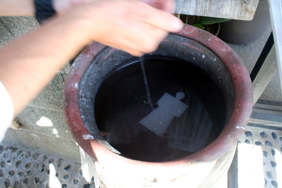 願いを込めながら静かに「玉の井」の神水を願い符にかける 願いを込めながら静かに「玉の井」の神水を願い符にかける