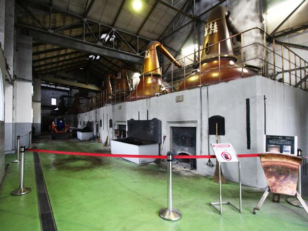 右上に見えるのがポットスチルの上部。パイプ部分は冷却器へつながる 石炭直火蒸留法が行われている蒸溜棟