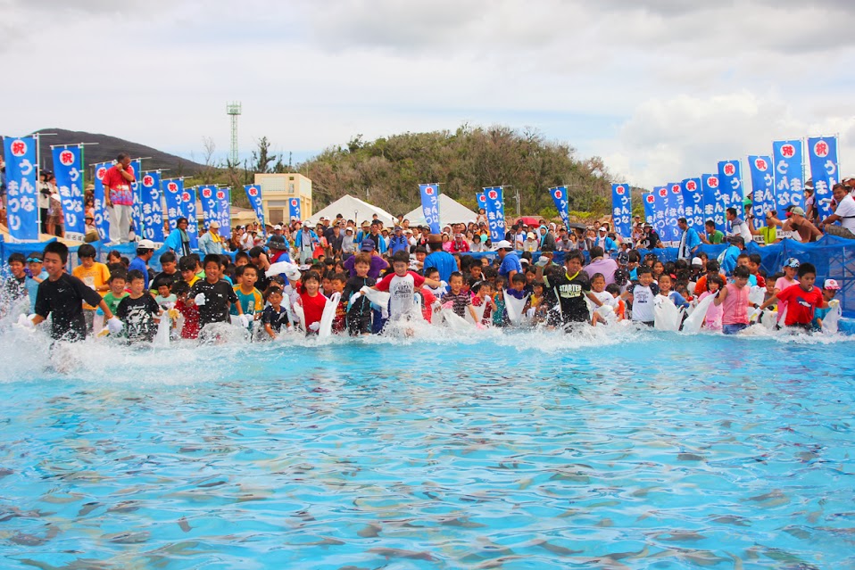 魚のつかみどりに挑戦しようと、つかみどり専用プールに駆け出す子供たち 魚のつかみどりに挑戦しようと、海に駆け出す子どもたち