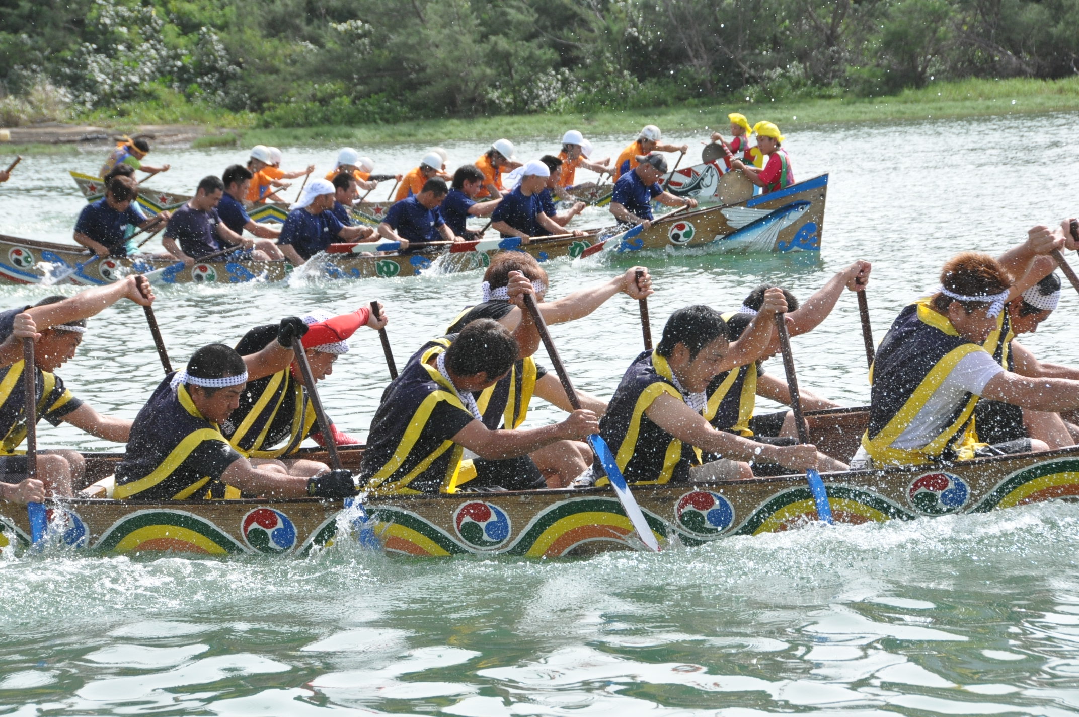 息を合わせてカイを漕ぐ。しぶきを上げて走る3隻のサバニ(伝統漁船) 息を合わせてカイを漕ぐ。しぶきを上げて走る3隻のサバニ。