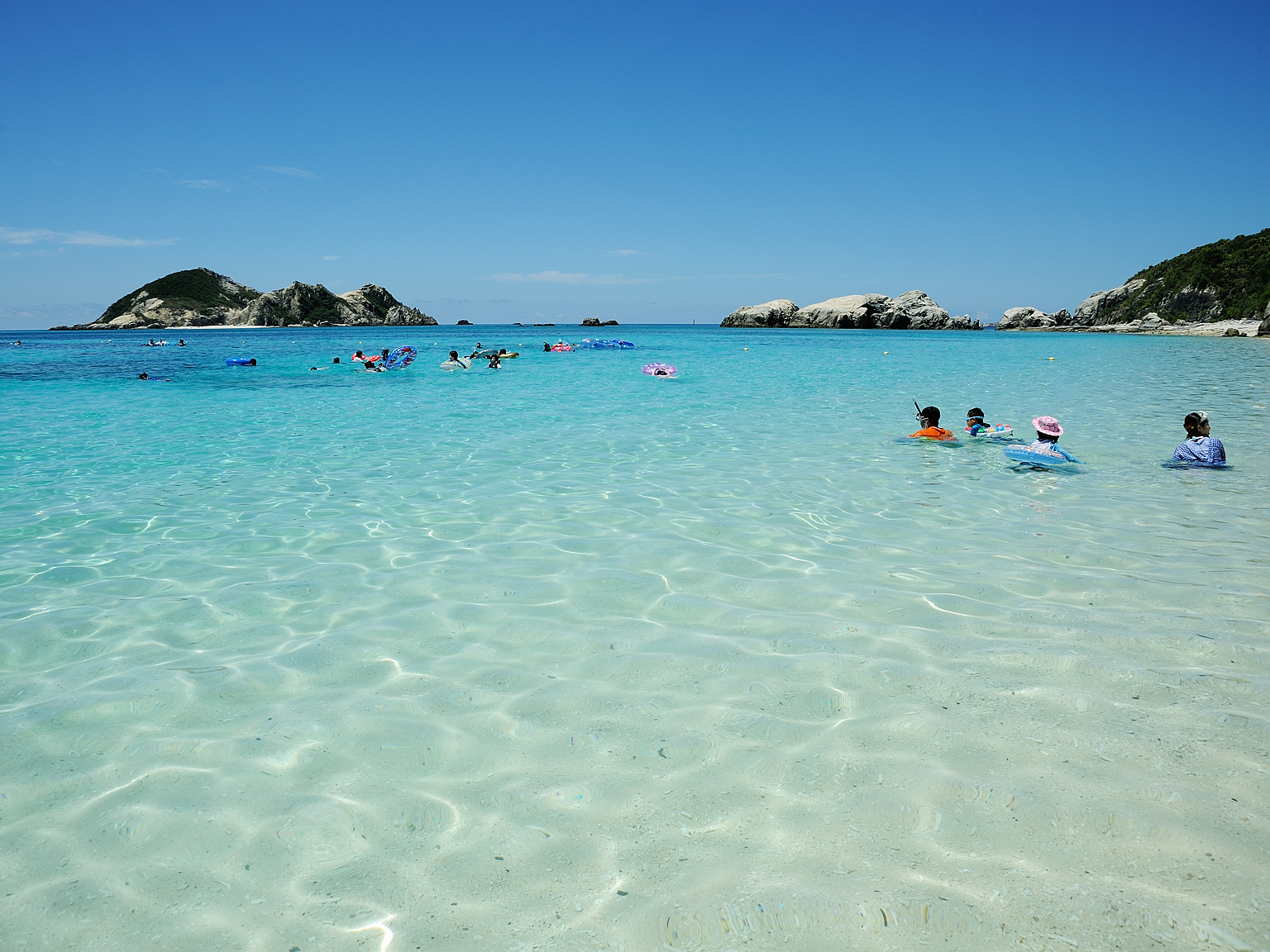 波打ち際から透き通った海が広がる。沖は無人島のハナレ 撮影/瀬戸口 靖 浜の近くの海が黒く見えるところがサンゴ礁。沖は無人島のハナレ