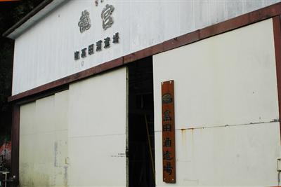 歴史を感じさせる富田酒造の蔵構えと、手彫りの看板