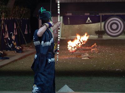 かがり火の中、矢を射る姿