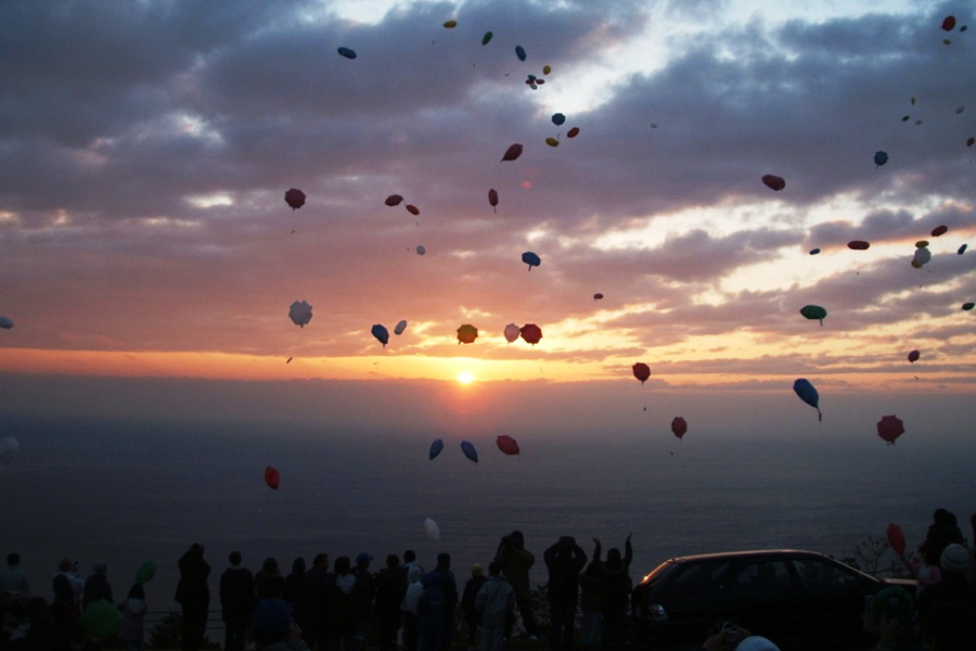 太平洋から昇る初の出とカラフルな紙風船が空を舞う感動的な光景が広がります 太平洋から昇る初の出とカラフルな紙風船が空を舞う感動的な光景