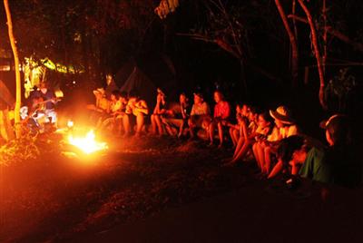 ヤンバルの森でキャンプファイアーの炎を囲む