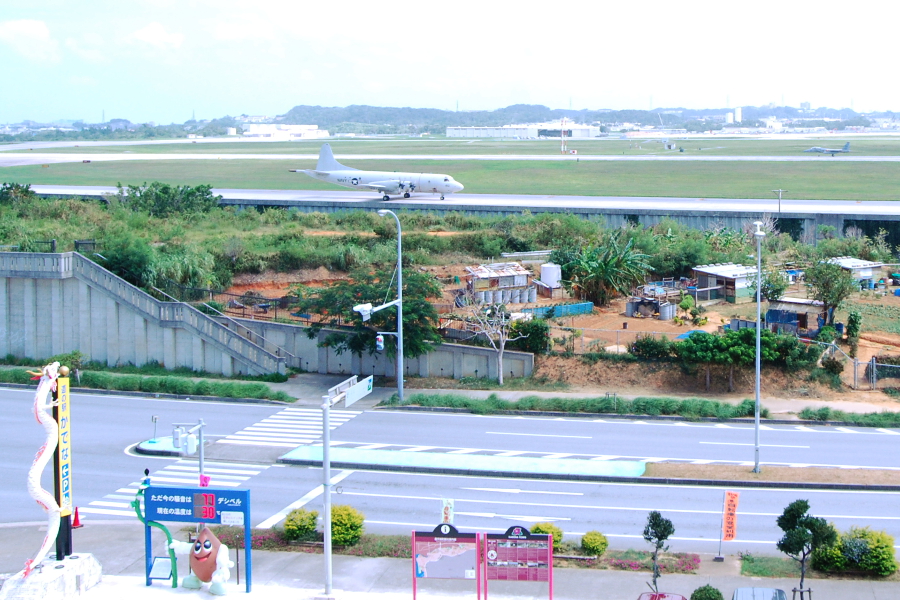 安保の丘と戦闘機と、騒音を表示する嘉手納町のキャラクター