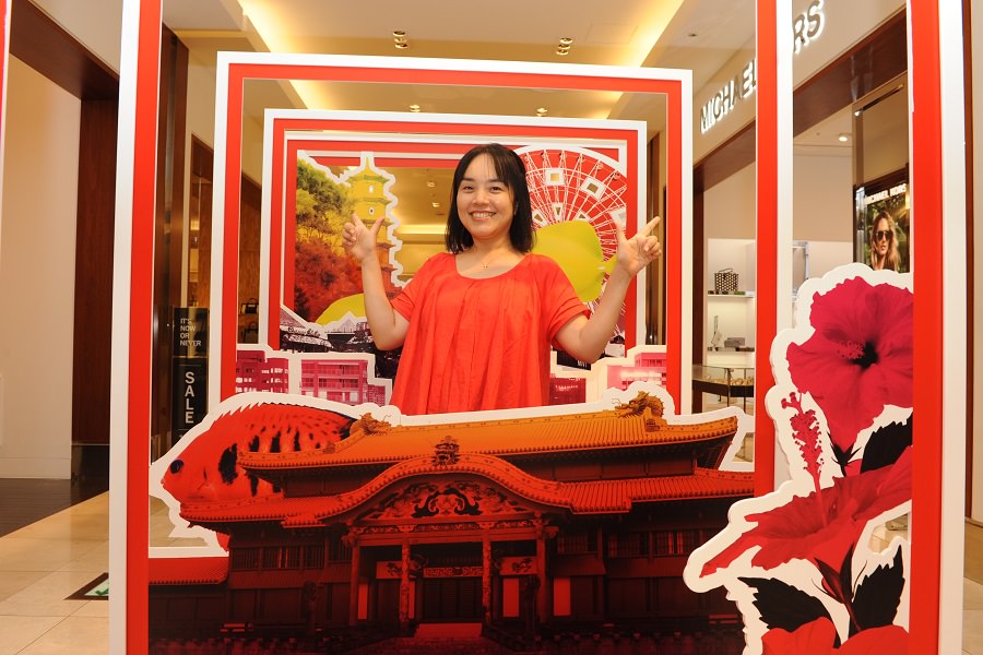 沖縄の名所を組みあわせたパネルの前で（パネルは期間限定）