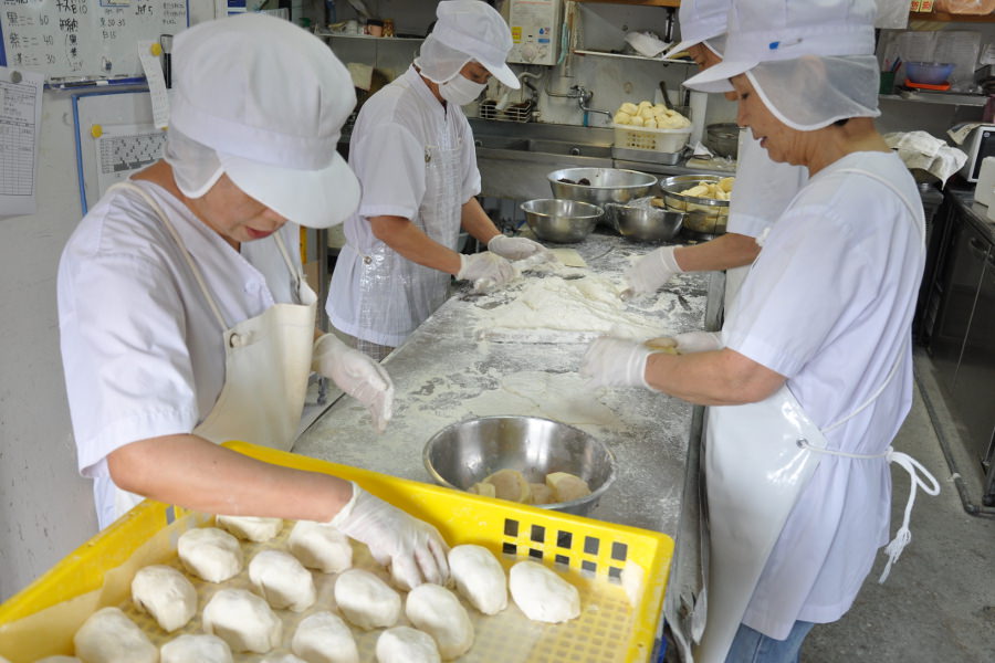 サツマイモとあんを一つ一つ手作業で生地に包み込む