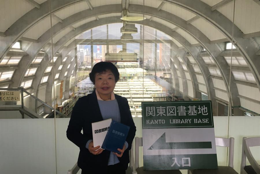 当館司書・轟良子さん。“作戦室”から館内書架を背景にして