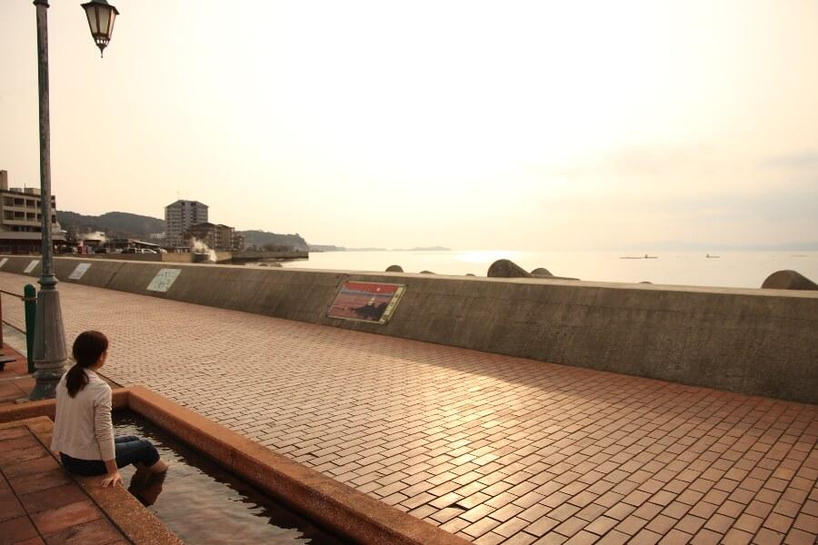 散策の締めは足湯でお待ちかねの夕日タイム。小浜温泉の熱量105度にちなんだ、105メートルの日本一長い足湯は、一般的な足湯の他、足ツボの刺激ができるウォーキング足湯やペット足湯などバラエティ豊富