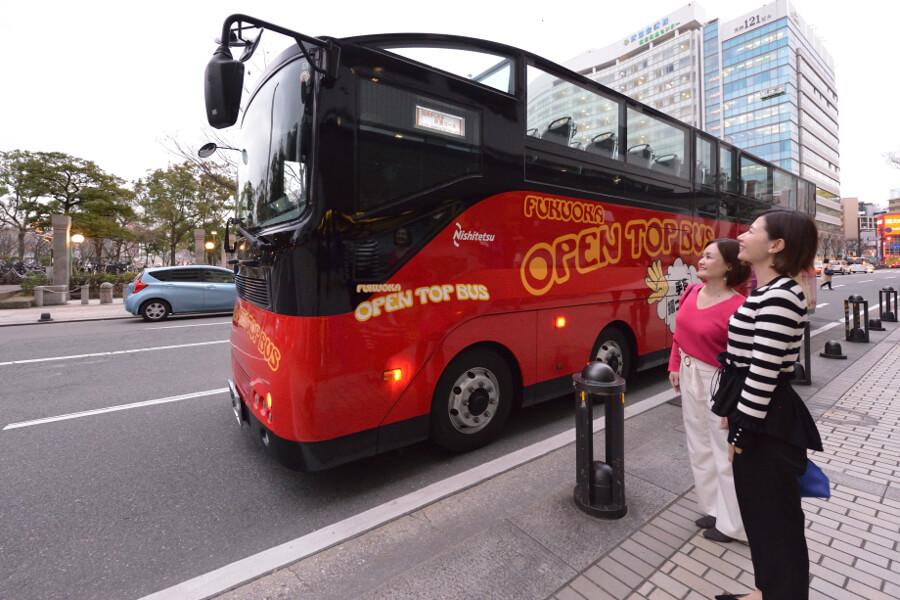 受付、出発は福岡市役所1階ロビーで。真っ赤なバスと、日が暮れ始める景色に、気分が高まります
